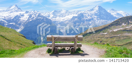 Scenic view of Swiss Alps with bench for taking view at Grindelwald First, Switzerland. Beautiful landscape in Jungfrau Region. famous Europe summer hiking trail and travel destination Scenic view of Swiss Alps with bench for taking view at Grindelwald First, Switzerland. Beautiful landscape in Jungfrau Region. famous Europe summer hiking trail and travel destination 141713420