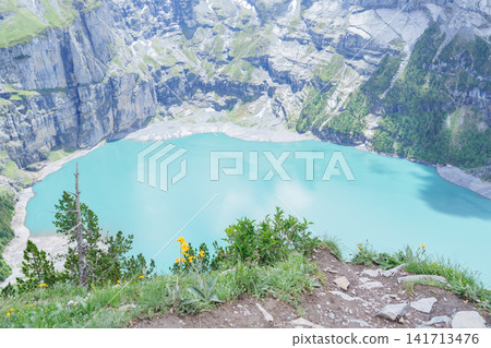 Scenic landscape of Oeschinensee or turquoise Oeschinen Lake in summer under blue sky with wildflowers and Stunning Swiss Alps. Spectacular green meadow hiking trail view, Kandersteg, Switzerland Scenic landscape of Oeschinensee or turquoise Oeschinen Lake in summer under blue sky with wildflowers and Stunning Swiss Alps. Spectacular green meadow hiking trail view, Kandersteg, Switzerland 141713476