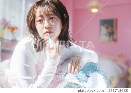 一位年輕女子麵無表情地塗著口紅。 141713688