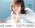 A young woman holding lipstick, smiles sweetly, and looks at the camera. 141713690