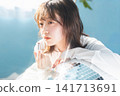 A young woman applies lipstick with an ennui expression. 141713691