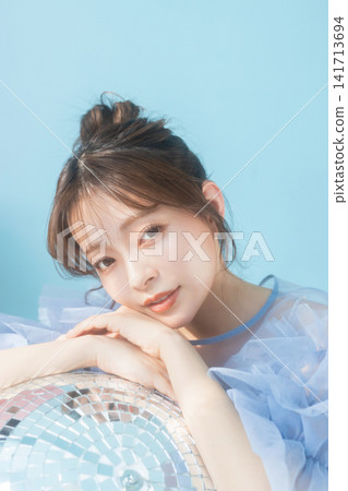 一位年輕女子麵帶微笑，穿著淺藍色連身裙。 141713694