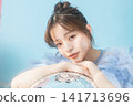 A young woman smiling, wearing a light blue dress. 141713696
