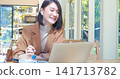 Happy asian woman video call web conference sitting on cozy sofa in living room at home. Smile Female asian people use laptop notebook computer headphones online call working from home watching video 141713782