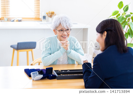 On-site appraisal service: A senior woman having her jewelry appraised at home. On-site appraisal service: A senior woman having her jewelry appraised at home. 141713894