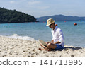 Man traveler use laptop on summer beach blue sky. Asian man casual blue short pants white shirt relax sitting summer beach. Man typing laptop computer holiday business trip freelance work on island 141713995