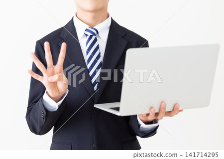 身穿西裝的年輕商人,手持筆記型電腦,伸出四根手指。 身穿西裝的年輕商人,手持筆記型電腦,伸出四根手指。 141714295