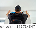 Air conditioner technician servicing wall mounted unit at home 141714347