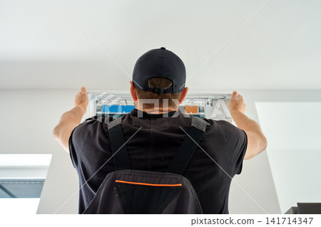 Air conditioner technician servicing wall mounted unit at home Air conditioner technician servicing wall mounted unit at home 141714347