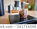 Coffee beans in glass container on digital kitchen scale 141714348
