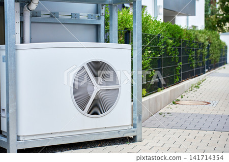 Outdoor heat pump unit installed beside residential building Outdoor heat pump unit installed beside residential building 141714354