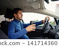 Man driving car to work with coffee in a reusable cup 141714360