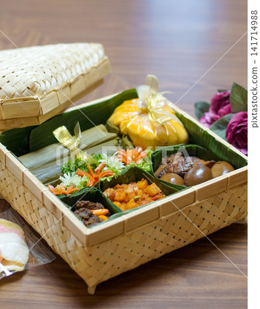 Traditional Indonesian food hamper with lontong, beef rendang, spicy potatoes, eggs and crackers presented in a bamboo basket for Ramadan, Eid, catering and festive family celebrations. Traditional Indonesian food hamper with lontong, beef rendang, spicy potatoes, eggs and crackers presented in a bamboo basket for Ramadan, Eid, catering and festive family celebrations. 141714988