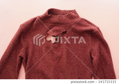 Sweater with a hole on a plain surface 141715315