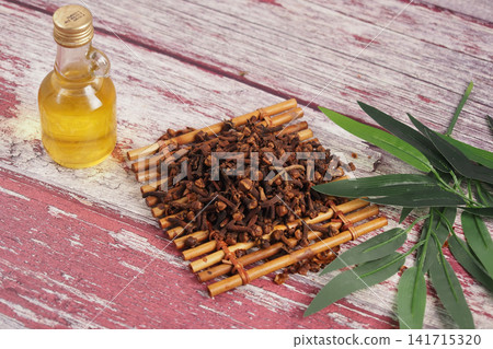 Clove oil and cloves on a wooden table with leaves Clove oil and cloves on a wooden table with leaves 141715320
