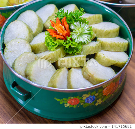 Close-up of lontong slices in a green enamel serving bowl, ideal for Indonesian food, recipe, and cultural cuisine themes. Close-up of lontong slices in a green enamel serving bowl, ideal for Indonesian food, recipe, and cultural cuisine themes. 141715691