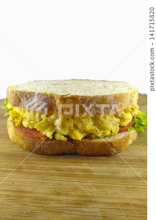Fresh egg sandwich with ham lettuce and tomato on wooden board isolated on white background breakfast concept. Fresh egg sandwich with ham lettuce and tomato on wooden board isolated on white background breakfast concept. 141715820