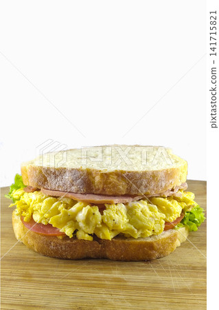 Fresh egg sandwich with ham lettuce and tomato on wooden board isolated on white background breakfast concept. Fresh egg sandwich with ham lettuce and tomato on wooden board isolated on white background breakfast concept. 141715821