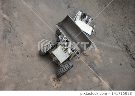 Aerial view of construction site where a front loader is loading soil, rocks, and debris into a dump truck, industrial work, excavation, and earthmoving processes Aerial view of construction site where a front loader is loading soil, rocks, and debris into a dump truck, industrial work, excavation, and earthmoving processes 141715958
