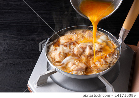 親子丼(雞肉雞蛋蓋飯)正在鍋中烹調(正在加入雞蛋) 親子丼(雞肉雞蛋蓋飯)正在鍋中烹調(正在加入雞蛋) 141716099