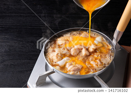親子丼(雞肉雞蛋蓋飯)正在鍋中烹調(正在加入雞蛋) 親子丼(雞肉雞蛋蓋飯)正在鍋中烹調(正在加入雞蛋) 141716102