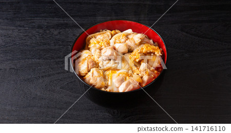 Oyakodon (chicken and egg rice bowl) on a black background Oyakodon (chicken and egg rice bowl) on a black background 141716110