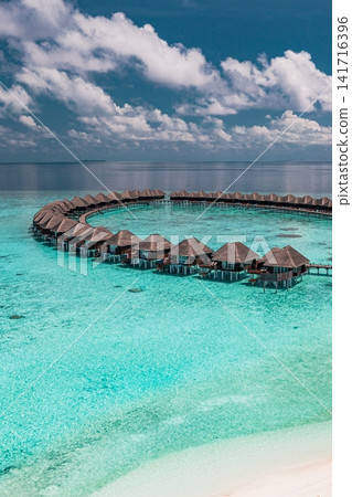 Spectacular aerial view of overwater villa loop across turquoise lagoon Maldives luxury resort tropical sea. Perfect summer vacation travel landscape paradise. Luxury honeymoon getaway scenic Spectacular aerial view of overwater villa loop across turquoise lagoon Maldives luxury resort tropical sea. Perfect summer vacation travel landscape paradise. Luxury honeymoon getaway scenic 141716396