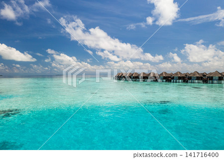 Stunning aerial view of overwater villas stretching across calm turquoise lagoon Maldives luxury resort horizon. Perfect summer vacation travel landscape paradise. Luxury honeymoon getaway scenic Stunning aerial view of overwater villas stretching across calm turquoise lagoon Maldives luxury resort horizon. Perfect summer vacation travel landscape paradise. Luxury honeymoon getaway scenic 141716400