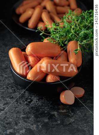 Boiled sausages with thyme on a black stone table. Boiled sausages with thyme on a black stone table. 141716436