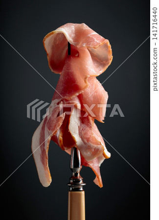 Raw fresh smoked pork bacon slices on a fork. Raw fresh smoked pork bacon slices on a fork. 141716440