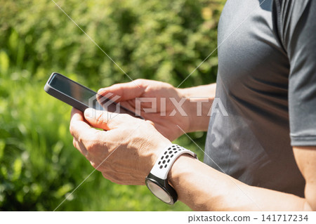 Close up of man using smartphone outdoors after cycling workout Close up of man using smartphone outdoors after cycling workout 141717234