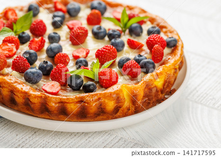 Homemade berry tart topped with fresh raspberries and blueberries Homemade berry tart topped with fresh raspberries and blueberries 141717595