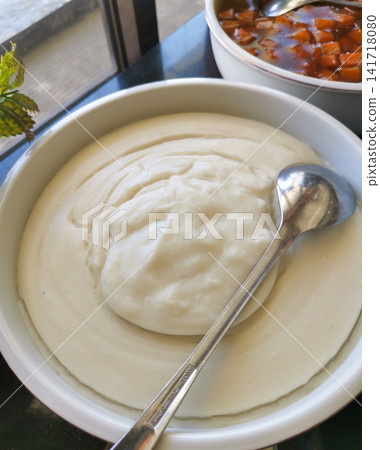 Authentic Indonesian bubur sumsum served in a ceramic bowl. Traditional creamy rice flour pudding suitable for food culture, hospitality, travel, culinary, and editorial projects. Authentic Indonesian bubur sumsum served in a ceramic bowl. Traditional creamy rice flour pudding suitable for food culture, hospitality, travel, culinary, and editorial projects. 141718080