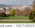 Panoramic Prague cityscape from a peaceful green park with Prague Castle and historic red rooftops in the distance, capturing scenic spring beauty of Prague City Czech Republic 141718429