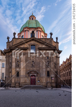 Historic Church of Saint Francis of Assisi with green Baroque dome in Prague City Czech Republic, showcasing ornate European architecture and a peaceful cobblestone square beneath a blue sky Historic Church of Saint Francis of Assisi with green Baroque dome in Prague City Czech Republic, showcasing ornate European architecture and a peaceful cobblestone square beneath a blue sky 141718435