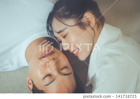 一對情侶在護膚後,閉上雙眼,臉貼著臉,在毯子上拍攝了一張以美容為主題的俯視肖像照。 一對情侶在護膚後,閉上雙眼,臉貼著臉,在毯子上拍攝了一張以美容為主題的俯視肖像照。 141718725