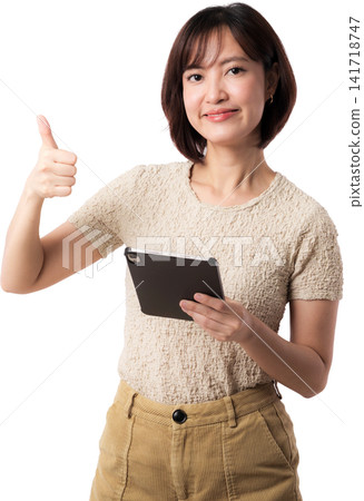 Asian woman tablet thumbs up portrait beige clothing showing cheerful expression against isolated background Asian woman tablet thumbs up portrait beige clothing showing cheerful expression against isolated background 141718747