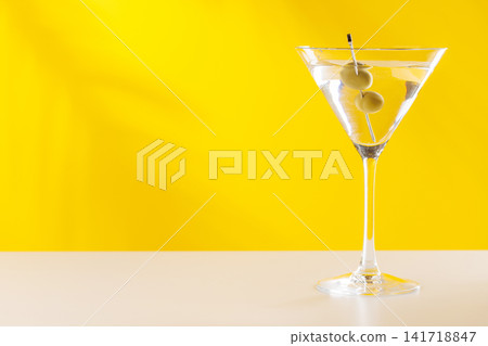 Classic martini cocktail with olives in glass on yellow background Classic martini cocktail with olives in glass on yellow background 141718847