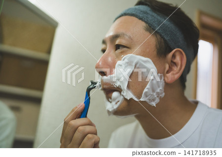 A 40-year-old man's facial care routine: applying shaving foam and carefully shaving the facial hair around his mouth. A 40-year-old man's facial care routine: applying shaving foam and carefully shaving the facial hair around his mouth. 141718935
