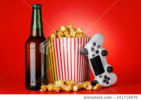 Popcorn and gamepad on red background Popcorn and gamepad on red background 141718970