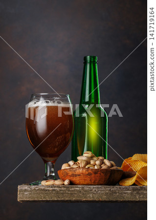 Beer glass with foam and bottle with pistachios Beer glass with foam and bottle with pistachios 141719164