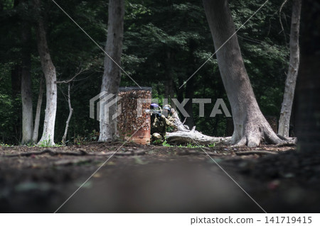 Player with paintball gun standing in the forest Player with paintball gun standing in the forest 141719415