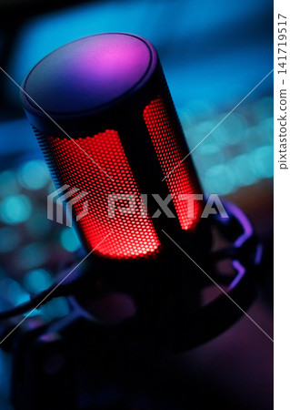 Dark cinematic macro of streamer mic on desk with RGB accent lighting Dark cinematic macro of streamer mic on desk with RGB accent lighting 141719517