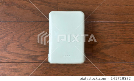 從正上方俯視的手機電池；木地板上的手機充電器。 141719582