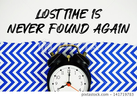 Lost Time is Never Found Again text written on paper with alarm clock on blue chevron background Lost Time is Never Found Again text written on paper with alarm clock on blue chevron background 141719783