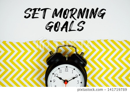 Set Morning Goals text written on paper with alarm clock on yellow chevron background Set Morning Goals text written on paper with alarm clock on yellow chevron background 141719789