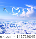 Airplane drawing heart in sky over the mountains. Jet flight route of aircraft in shape of heart. Heart-shaped flight path drawn by plane. Topic of holiday, travel, trip abroad on vacation, tour 141719845
