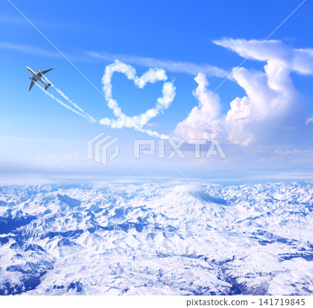 Airplane drawing heart in sky over the mountains. Jet flight route of aircraft in shape of heart. Heart-shaped flight path drawn by plane. Topic of holiday, travel, trip abroad on vacation, tour Airplane drawing heart in sky over the mountains. Jet flight route of aircraft in shape of heart. Heart-shaped flight path drawn by plane. Topic of holiday, travel, trip abroad on vacation, tour 141719845