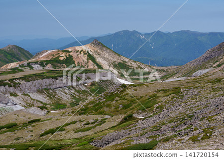 A stunning summer scene: The snow-covered ridge trail from Mt. Akadake to Mt. Hakuunzan in Hokkaido's Daisetsuzan Mountains. A stunning summer scene: The snow-covered ridge trail from Mt. Akadake to Mt. Hakuunzan in Hokkaido's Daisetsuzan Mountains. 141720154