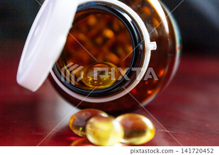 Pills spilling out of a bottle isolated on dark background, Vitamin for health Pills spilling out of a bottle isolated on dark background, Vitamin for health 141720452